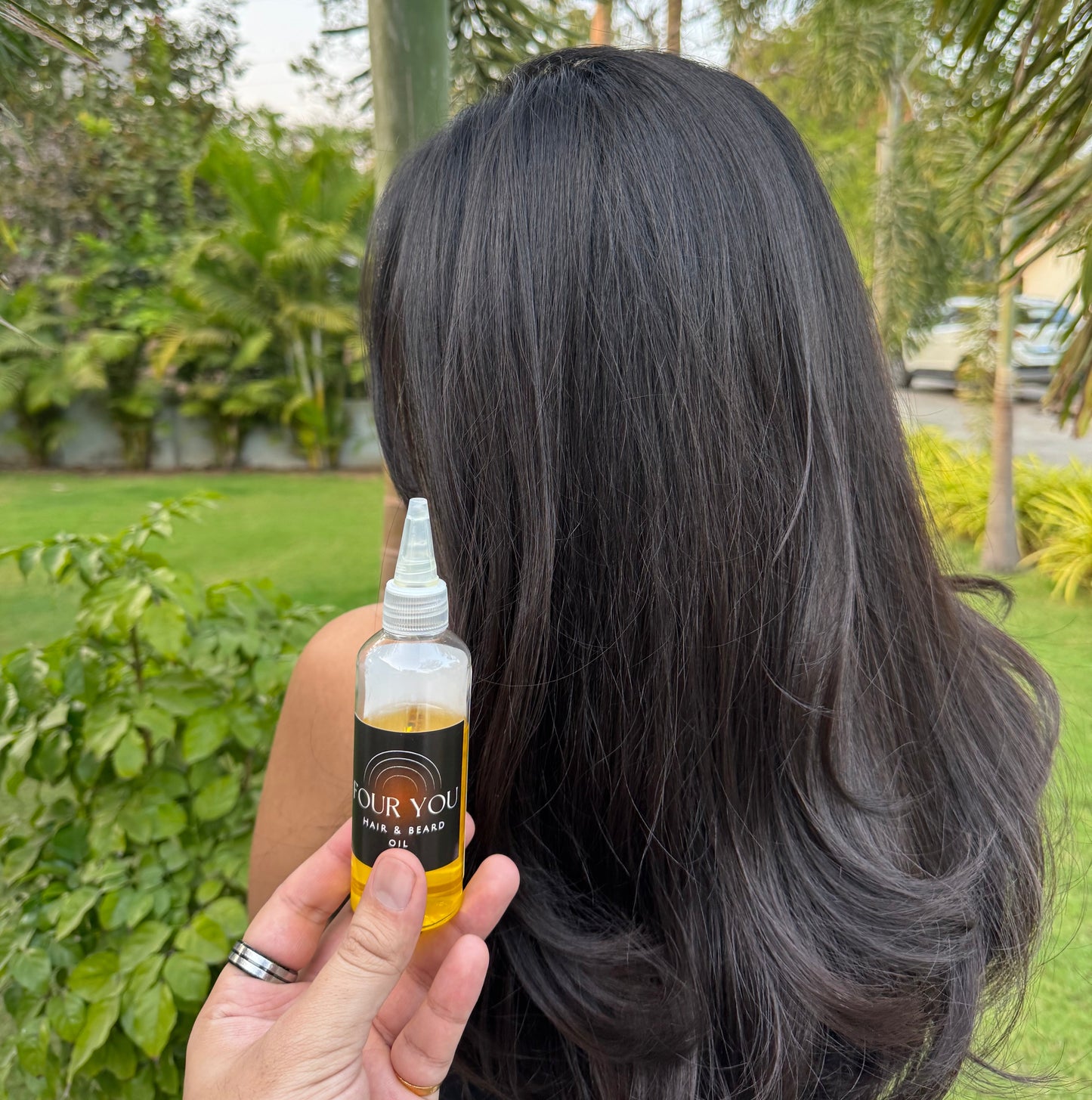 long brown healthy hair with hair oil bottle next to hair